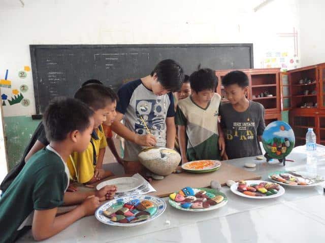 ครูจีนหัวใส ฝึกนักเรียนสร้างผลงานศิลปะจากก้อนหิน แลกเสื้อกันหนาว